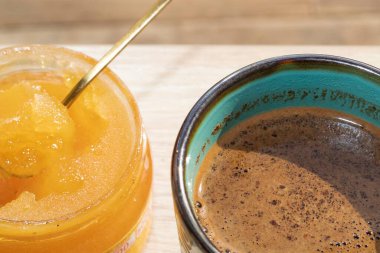 Tahta masada bal kavanozlu bir fincan kahve.