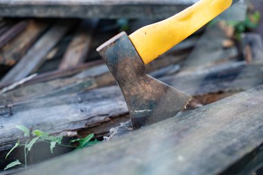 Tahtaya saplanmış sarı saplı balta. El işçiliği ve ahşap işçiliği kavramı.
