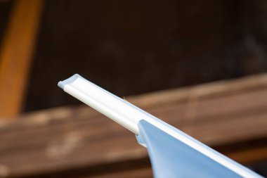 Camları temizlemek için cam sileceği kullanan biri. Mavi eldiven, cam yüzeydeki suyu temizliyor..