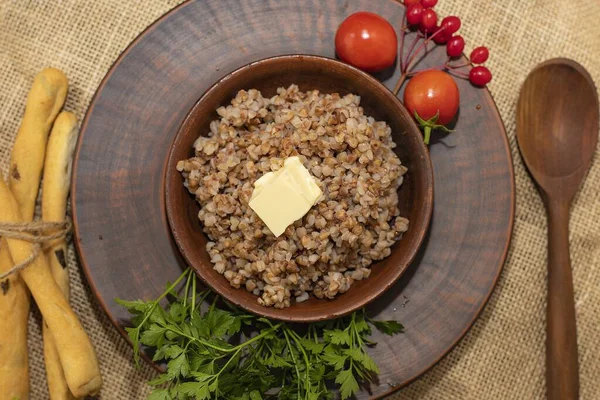 Haşlanmış karabuğday lapası, kırsal masada seramik kasede tereyağlı.