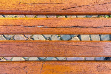 Çatlak ve turuncu boyalı eski ahşap bankın yakın görüntüsü, doğal kırsal doku yaratıyor..