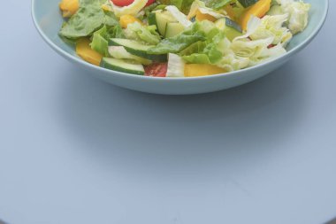 Sağlıklı sebze salatası, salatalık, dolmalık dolma biber ve domates, mavi bir kasede servis edilir..