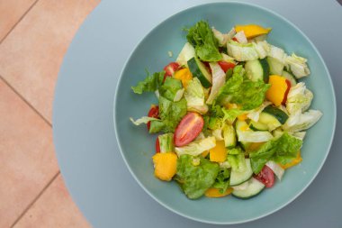 Sağlıklı sebze salatası, salatalık, dolmalık dolma biber ve domates, mavi bir kasede servis edilir..