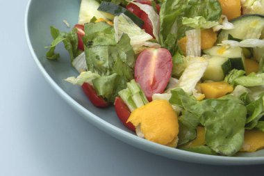 Sağlıklı sebze salatası, salatalık, dolmalık dolma biber ve domates, mavi bir kasede servis edilir..