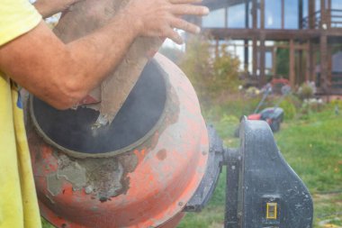 İnşaat alanında beton karıştırıcıya çimento döken işçiler inşaat konsepti, el işçiliği ve inşaat malzemeleri. Endüstriyel ve mühendislik temaları için mükemmel.