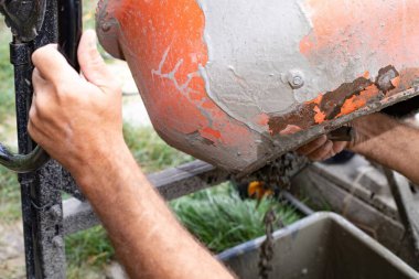 İşçi inşaat alanındaki çimento karıştırıcıdan ıslak beton döküyor. İnşaat, inşaat malzemeleri ve endüstriyel çalışma kavramı.