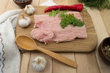 Çiğ tavuk kıyması, biberli sarımsak ve maydanozlu ahşap kesim tahtası.