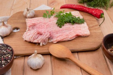 Çiğ tavuk kıyması, biberli sarımsak ve maydanozlu ahşap kesim tahtası.