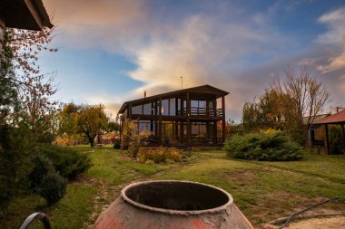 Sonbahar akşamları bahçesinde cam pencereli modern ahşap ev