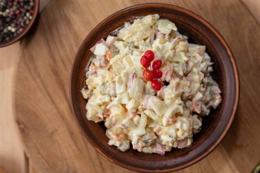 Geleneksel Olivier salatası ve mayonez kahverengi seramik kâse içinde ahşap masada servis edilir.