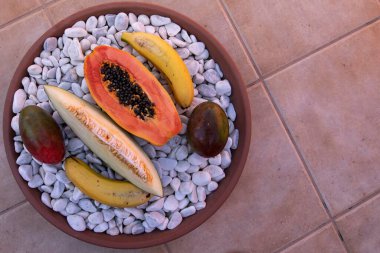Tropikal meyveler papaya muz mangosu ve kavun beyaz taşlarda