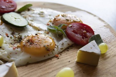 Tahtada kızarmış yumurta, sebze ve peynir dilimleri.