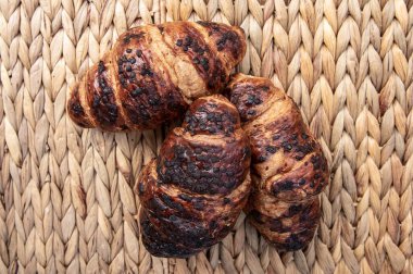 Üç çikolatalı kruvasan örülmüş hasır arka planda yakın plan