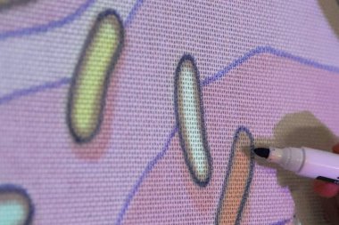 Projektör ve işaret kullanılarak kumaşa halı tasarımı çiziliyor