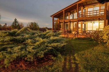 Sonbahar kırsalında geniş pencereli modern ahşap ev