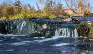 Temiz suyu olan küçük bir şelale ve güneş ışığında yeşil yosun.