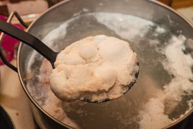 Mutfak kaşığıyla kaynayan et suyundan köpük çıkarılıyor.