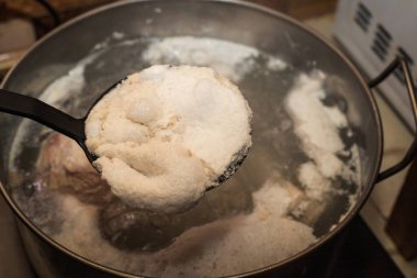 Pişirme işlemi sırasında kaynatma kaşığıyla köpük çıkarılıyor