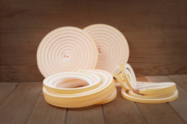 Termal yalıtım köpüğü. Ev onarımı için ahşap yüzeye yerleştirilmiş şerit ruloları.