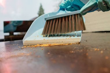 Lastik eldiven içinde fırçayla faraş kırıntıları süpürüyor.