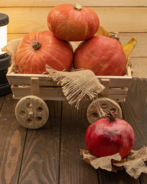 Tahta arabadaki sonbahar balkabakları yapraklar ve ahşap arka planda kırsal dekorlar.