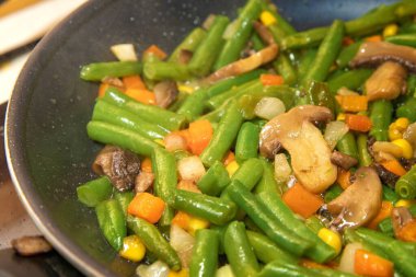 Yeşil fasulyeli havuçla karışık sebzeler tavada pişmiş mısır ve mantar.