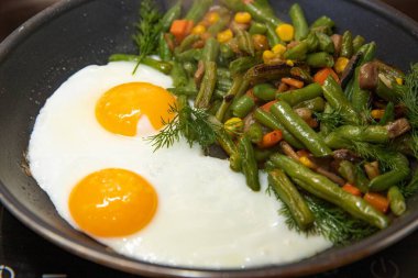 Kızarmış yumurta ve sebze karışımı yeşil fasulye havuç mısır ve bitkiler tavada