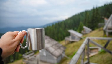 Metal kamp kupası yumuşak sisli dağ manzarasıyla el ele tutuştu.