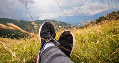 Dağdaki çayırlarda dinlenen siyah spor ayakkabıların rahatlatıcı manzarası.