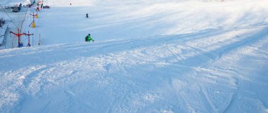 Kar yamacındaki kayakçılar soğuk açık bir günde dağınık kar oluşumlarıyla