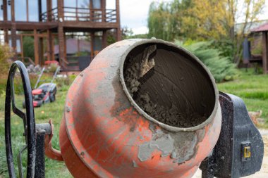 Ahşap evin yanındaki inşaat alanında taze betonla çimento karıştırıcısı.