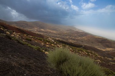 Volkanik yamaçları ve yumuşak güneş ışığında sisli vadisi olan dağ manzarası