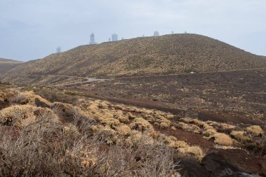Kuru bitki örtüsüyle volkanik yamaçlar ve Teide Gözlemevi 'ne giden dolambaçlı dağ yolları..