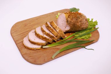 Tahtada dilimlenmiş domuz filetosu, baharatlı otlar ve taze garnitürle.