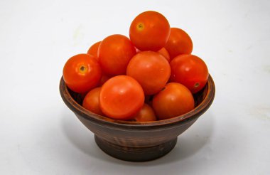 Kırsal seramik kasede taze olgun domatesler temiz beyaz stüdyo arka planına yerleştirilmiş.