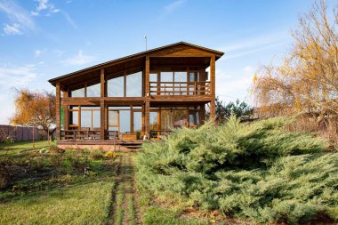 Sonbahar bahçesinde geniş panoramik pencereli modern ahşap kır evi