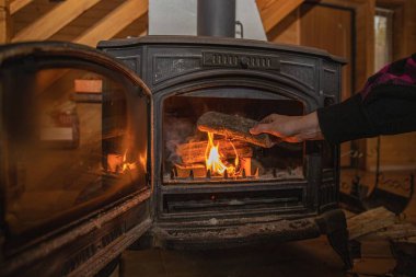Sıcak ahşap iç kısımda yanan odun sobasına odun koymak.