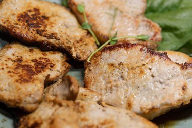 Izgara domuz eti dilimleri ve sıcak, leziz yemek takımında otlar.