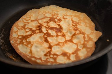Ev yapımı kahvaltı sırasında sıcak tavada kızaran altın gibi ince krep.