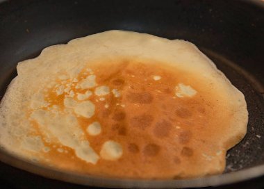 Ev yapımı kahvaltı sırasında sıcak tavada kızaran altın gibi ince krep.