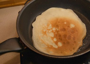 Ev yapımı kahvaltı sırasında sıcak tavada kızaran altın gibi ince krep.