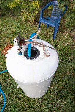 Bahçe temizliği görevlerinde kullanılan mavi hortumlu plastik su tankı.