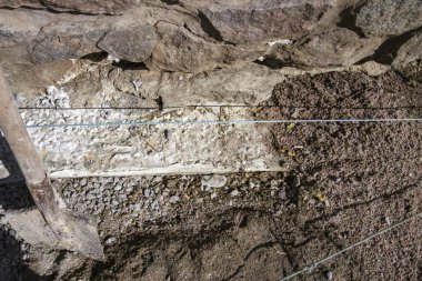 Taştan duvar katmanları ve inşaat aletleriyle kıyı takviyesi onarım süreci