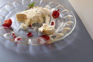 Cam tabakta servis edilen kremalı vanilyalı tatlı ahududu ve taze naneli garnitür.