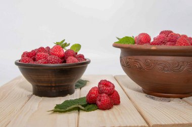 Ahşap masadaki kil kasede ahududu taze, tatlı yaz yemeği kompozisyonu yaratır.