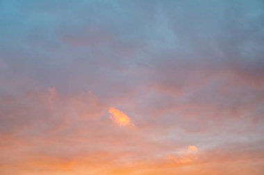 Yumuşak renkli günbatımı gökyüzü ve yumuşak bulutlar ılık atmosferik akşam arkaplanı oluşturur.