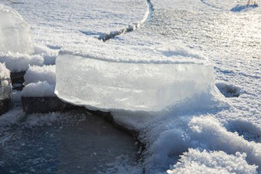 Donmuş buz bloğu yüzeyi, detaylı kristal donuyla kaplı. Doğal kış dokusu arka planı oluşturuyor.