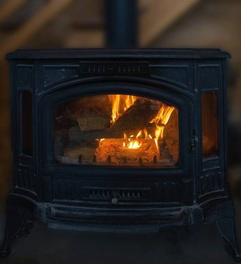 Yanan ahşap kütükler dökme demir soba sıcak, sade kış atmosferi yaratır.