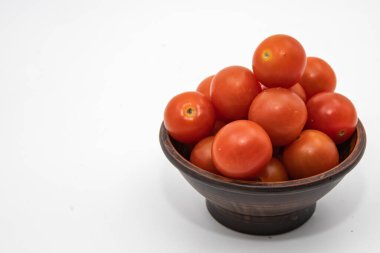 Taze kırmızı domatesler, beyaz arka planda koyu ahşap bir kasede istiflenmiş.