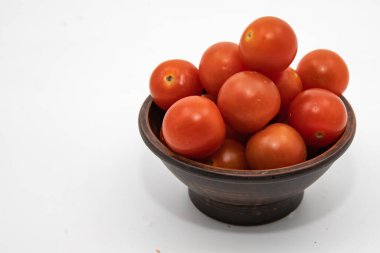 Taze kırmızı domatesler, beyaz arka planda koyu ahşap bir kasede istiflenmiş.